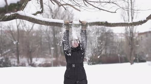 A Woman with a Smile Hanging From a Tree Branch in the Snowy Winter Atmosphere