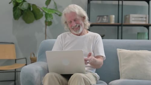 Senior Adult Video Calling on Laptop from Couch