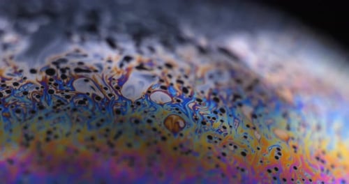 L'iris multicolore d'une bulle de savon est en mouvement. Bulle de savon réaliste, éblouissement. Macro à bulles extrême.