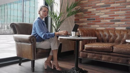 Stilvolle Unternehmerin sitzt mit Laptop im Café