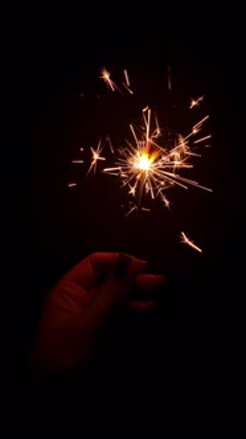 Hand Holding a Brightly Burning Sparkler Against a Black Background Celebration of New Year's Eve