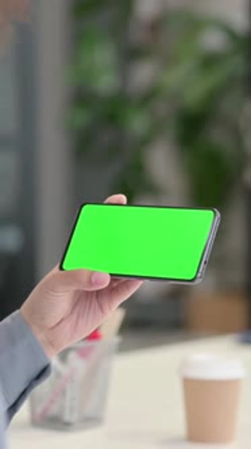 Vertical Rear View of African Woman Looking at Smartphone with Green Chroma Key Screen