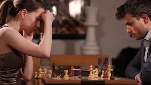 Dame in braunem Kleid spielt hartes Schach, um den Geschäftsmann in einem Schachspiel schachmatt zu setzen. Nahaufnahme