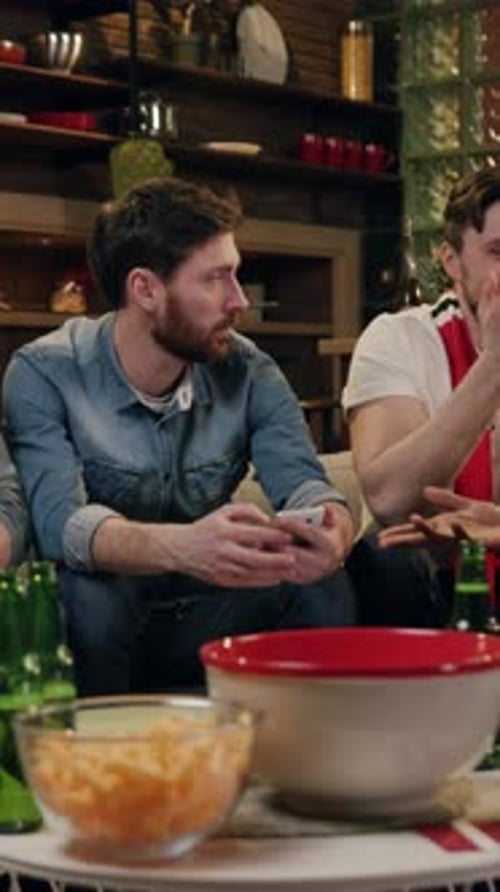 Men Sitting with Phones and Snacks Indoors