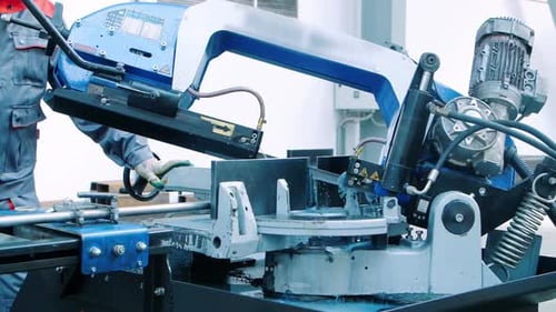 Worker Operating Hack Saw Cutting Machine. Metal Cutting Machine With Cooling System. Factory Wor...