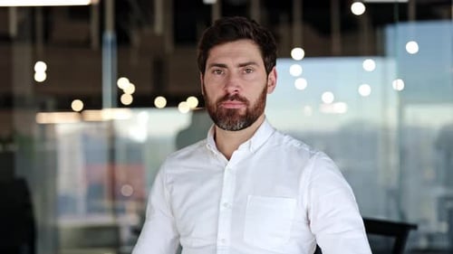 Selbstbewusster Geschäftsmann lächelt mit verschränkten Armen in einem modernen Büro