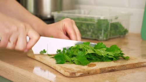Chopping Fresh Parsley on Cutting Board in Kitchen
