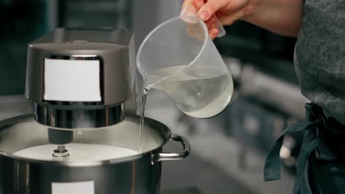 Closeup of Hands in a Professional Kitchen Over an Iron Table a Baker Pours Water Into the Machine