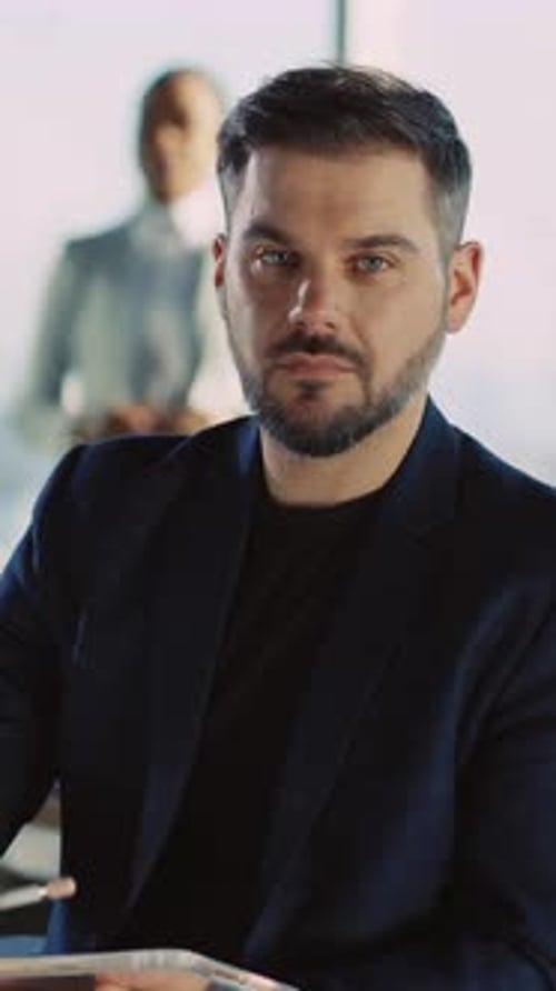 Professional Man Smiles Holding Tablet in Office Setting
