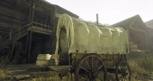 Un vagón rústico se encuentra cerca de antiguas estructuras de madera en un paisaje iluminado por el sol