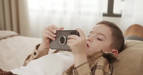 Child Lying on Bed Using Mobile Phone