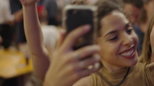 Três lindas garotas filmando com um smartphone enquanto sorriem e dançam