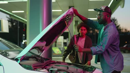 Vérification du compartiment moteur de la voiture à la station-service la nuit