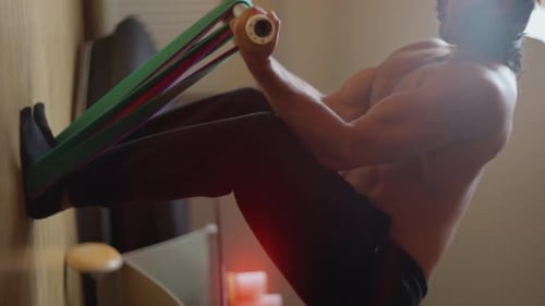 A Man is Engaged in a Workout Routine at Home Making Use of Resistance Bands to Exercise