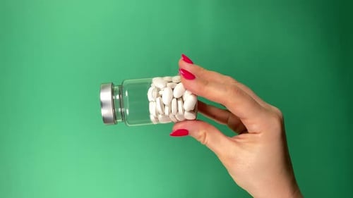 Hand Holding Vial of White Pills