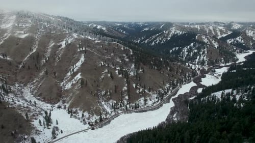 Cold and Snowy Winter Canyon with snow and road running through- aerial