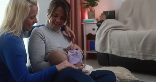 Happy female gay couple having tender moment with their baby son at home