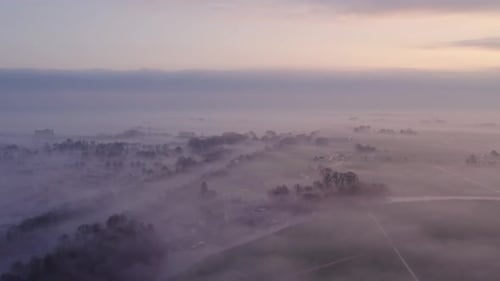 Aerial view of foggy fields and village at sunrise, Netherlands.