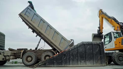 Dump truck unload cargo into special container, side view