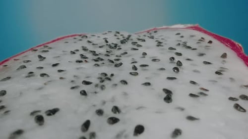 Zoom out over a dragon fruit (Pitaya) slice on blue background. slider with probe lens.