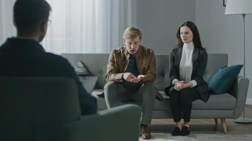 Young Couple on a Counseling Session with Psychotherapist. Back View of Therapist Taking Notes: Ang