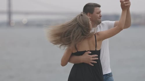 A Cute Smiling Married Couple Dancing on the Pier in Cloudy Weather