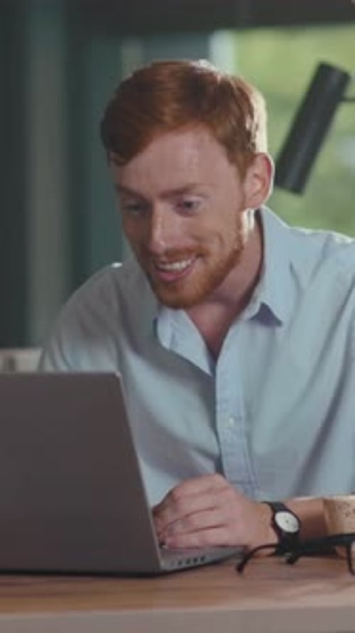 Excited Young Man Using Laptop at Desk