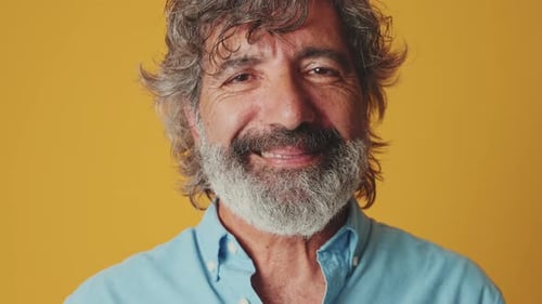Close up portrait, elderly man, looking camera smiling, isolated on an orange background