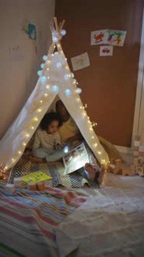 Child Reads Book in a Blanket Fort at Night