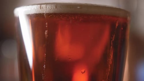 Close up of beer pouring into a pint glass and swirling bubbles rising in it 4K