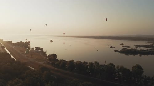 Stunning 4K aerial footage of a drone filming hot air balloons. Flying over farming fields and river