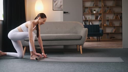 Woman Rolling Up Yoga Mat After Exercise at Home