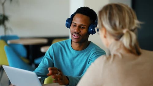 Une femme et un homme discutent d'un projet collaboratif en ligne sur leur lieu de travail