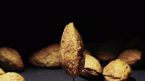 Almonds in shells rotate on a black background. Almonds are thrown on the table. Close-up