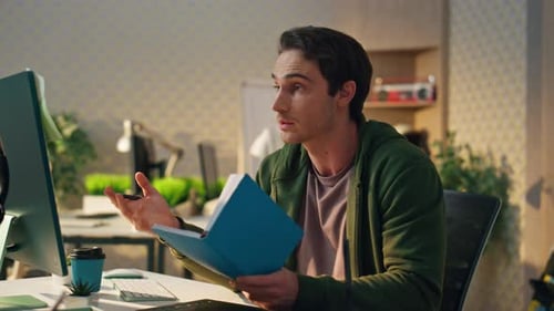 Creative startup man reads notebook and enjoys virtual meeting at informal office
