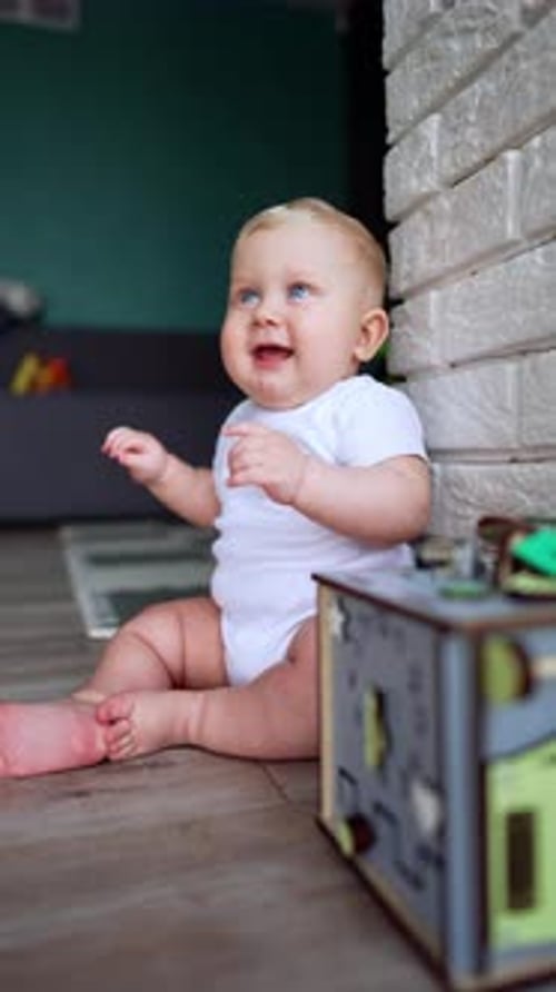 Happy Blond Infant Playing with Toy Indoors