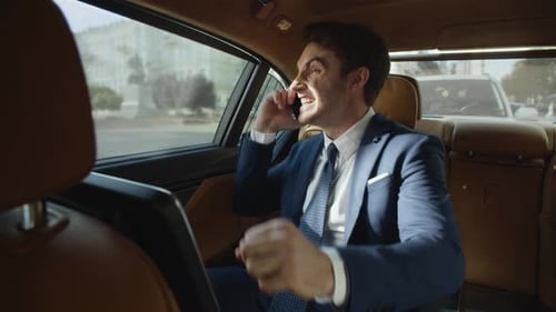 Excited man celebrates success on phone in car