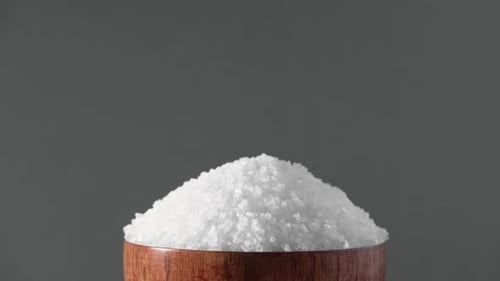 White Table Salt Granules Falling Into a Pile Wood Bowl Gray Color Studio Background Condiment