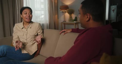 Woman Conversing with a Man Indoors on a Couch