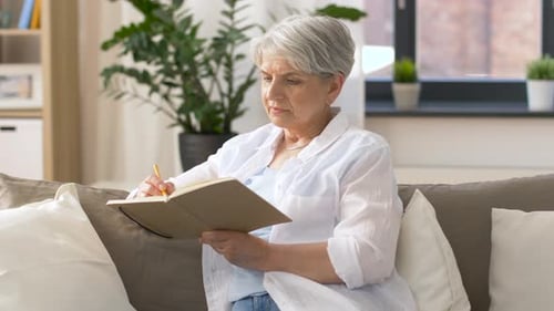 Senior Woman Sitting on Couch Writing in Journal