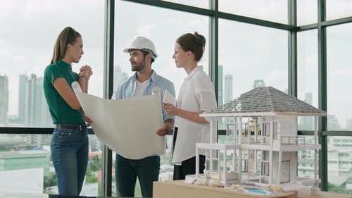 Architects Reviewing Blueprints and House Model in Office
