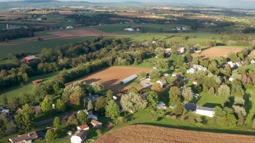 Summer aerial of rural town, village in USA among farmland. Beautiful golden hour light and shadows.