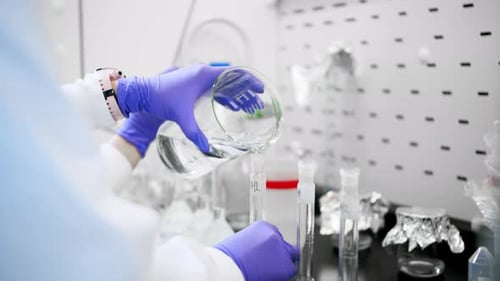 A lab scientist pours liquid into containers during the search for a cure.