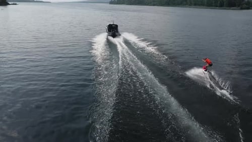 A Young Man Rides a Wakeboard A Sports Guy Rides on the Water on a Board Behind a Boat Top View From
