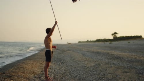 Young Adult on Beach Holding Pirate Flag at Sunrise