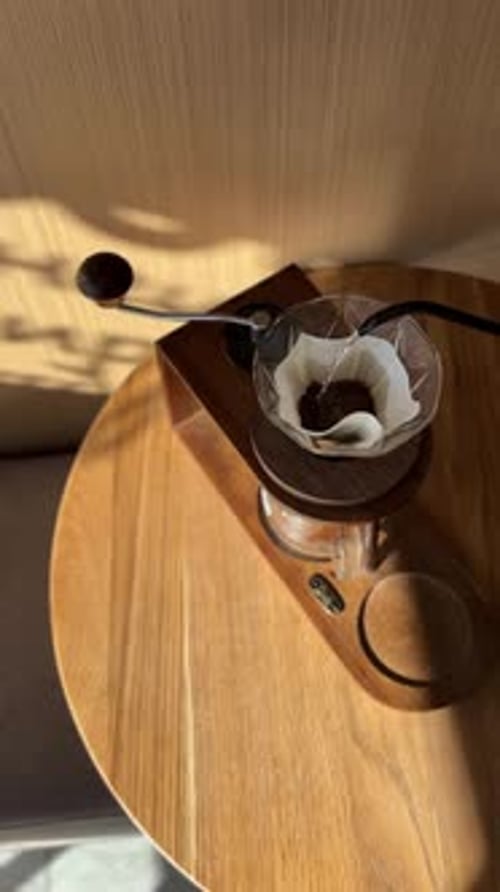 Top View Pouring Water From Black Kettle in V60 Paper Filter with Fresh Grind Coffee Beans on the
