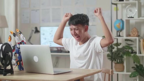 Asian Boy Celebrating Succeed Working About A Cyborg Hand On A Laptop At Home
