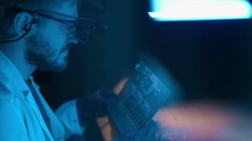 Man Examining Computer Circuit Board in Lab