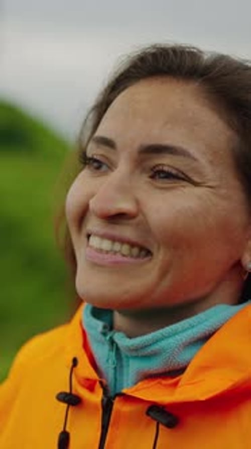 Une résilience joyeuse Une femme embrassant la splendeur de la nature tout en enfilant une veste de pluie orange vif dans un