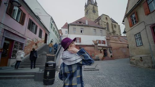 Woman admires views of old town buildings in the middle of the street.